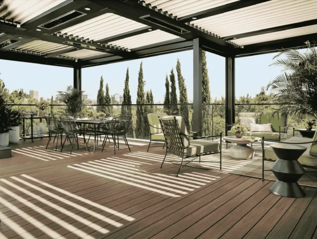 deck builder in St. Paul — covered outdoor deck with metal louvered pergola, composite decking, glass railing, dining table and cushioned lounge seating